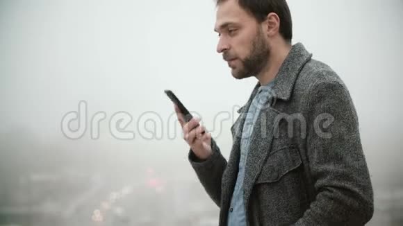 站在法国巴黎埃菲尔铁塔附近的年轻人雾蒙蒙的早晨男性与某人在手机上交谈视频的预览图