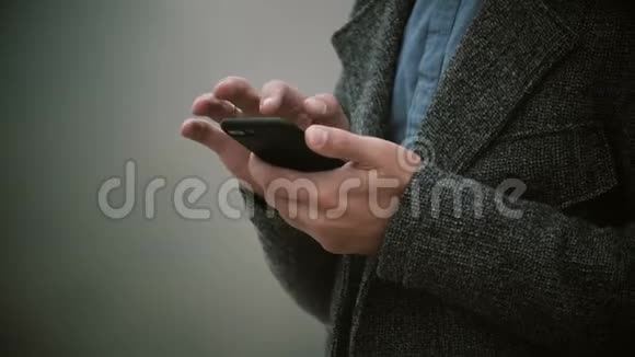 雾蒙蒙的早晨男性手握着手机的特写镜头时髦的男人使用带有触摸屏的智能手机视频的预览图