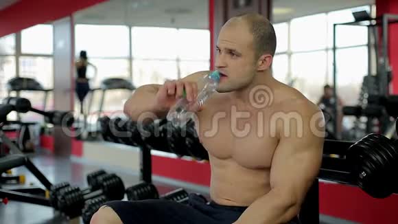 肌肉男在健身房积极锻炼后饮用淡水健康的生活方式视频的预览图