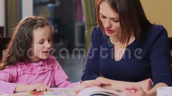 特写妈妈教小女儿看彩书视频的预览图