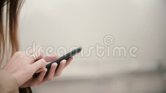 近距离观看女性手拿手机与触摸屏在雾天公园用智能手机的女人视频的预览图