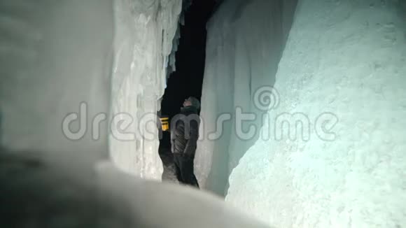 在贝加尔湖冰洞旅行的人去冬岛旅行背包客正在冰窟散步旅行者看着视频的预览图