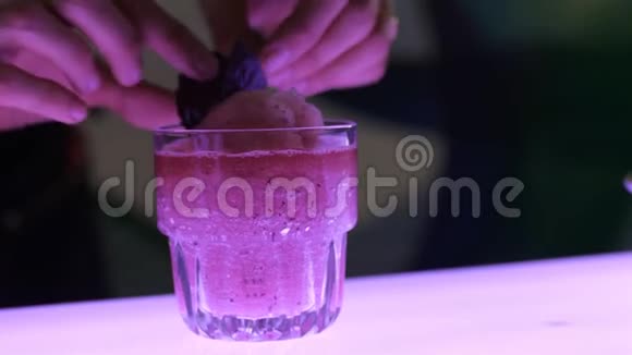 在准备鸡尾酒的过程中酒保用柔和的鸡尾酒装饰红罗勒的叶子视频的预览图