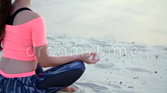 女人坐在海边放松瑜伽姿势特写视频的预览图