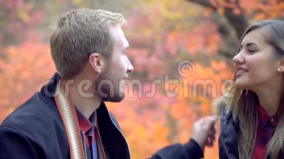 秋天公园里长胡子的男人拥抱一个快乐的女人在她耳边低语慢动作视频的预览图