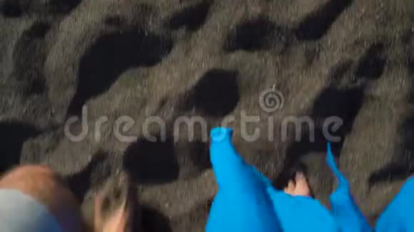 两人在海边的黑色火山沙上漫步的最佳景观视频的预览图