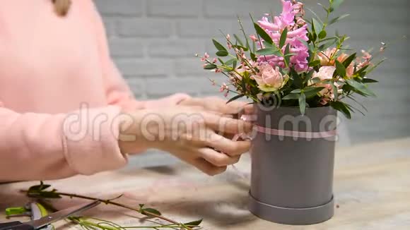 女性的双手用鲜花在盒子里摆花边蝴蝶结视频的预览图