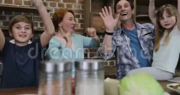 快乐的家庭在厨房里举手做饭一起吃饭快乐的微笑父母有两个孩子视频的预览图