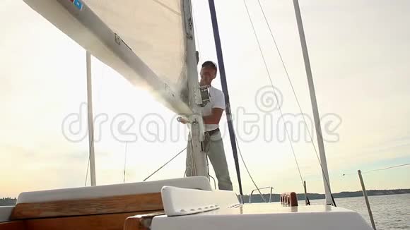 在船上游艇上旅行中举起主帆的老人视频的预览图