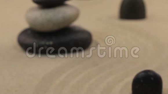 走近由石头和黑色石头组成的金字塔矗立在曲折的沙子上视频的预览图