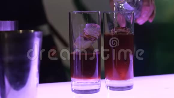 鸡尾酒的制作过程酒保在两个玻璃杯中用冰盖烹制鸡尾酒这是毒气的矿物视频的预览图