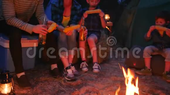 美国家庭在大火附近吃炸玉米进入森林年轻的父母带着孩子吃玉米喝啤酒视频的预览图