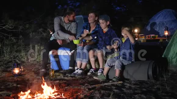 有孩子的父母把zephyr放在林地篝火附近的扦子上家人交流并放棉花糖视频的预览图