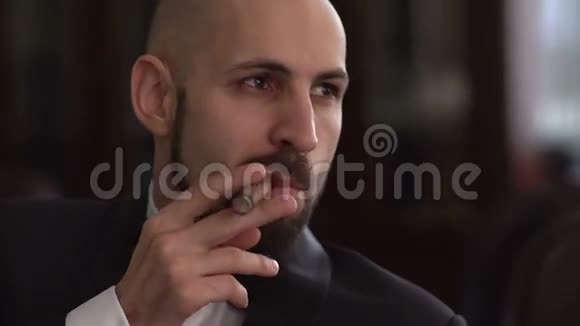 英俊的老板坐在扶手椅上抽雪茄慢动作视频的预览图