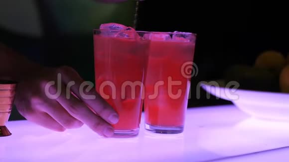 在做鸡尾酒的过程中酒保依次端着两个杯子中的一个用一个加冰的熟鸡尾酒视频的预览图