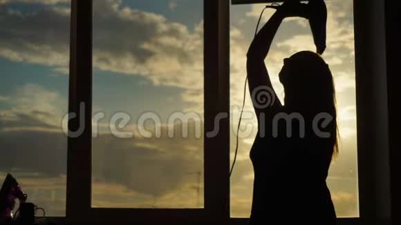 一位中年妇女在日落时分烘干吹风机视频的预览图