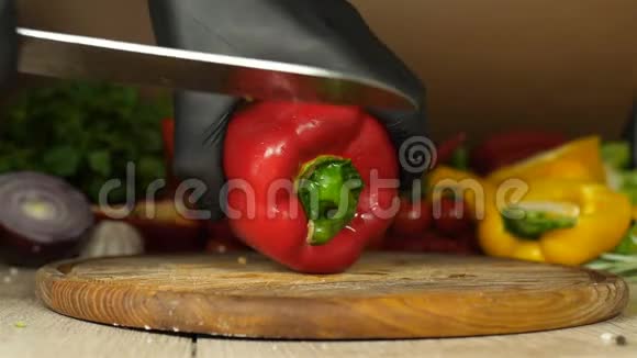 厨师戴着黑色手套手里拿着一个多汁的红辣椒它躺在木板上把辣椒上的穗子剪掉视频的预览图
