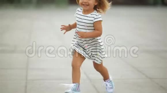穿着连衣裙和蓝色运动鞋的金发小女孩正跑向穿着红色鞋子的母亲从脚的角度看视频的预览图