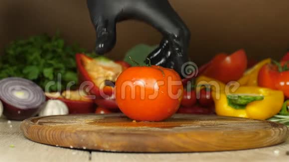 带着黑色手套的厨师把一个多汁的红番茄在他的轴上滴着水滴一个特写番茄躺在上面视频的预览图