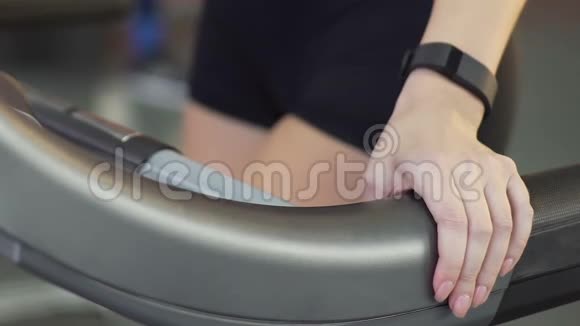 女孩在跑步机上行走同时保持手柄体重控制和身体护理视频的预览图
