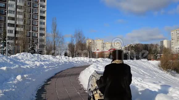带着婴儿车的女人走在俄罗斯莫斯科的林荫大道上视频的预览图