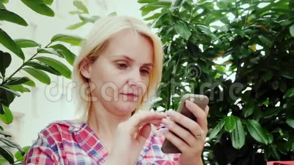 一位年轻女子在咖啡馆的夏季露台上使用智能手机的肖像欧洲旅游业格拉茨市视频的预览图