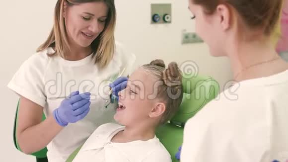 儿科牙医在办公室里看牙椅女孩照镜子微笑视频的预览图