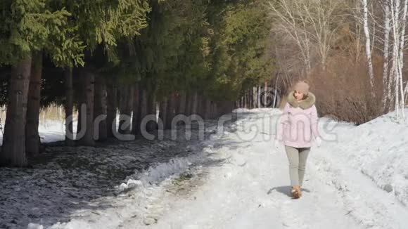 幸福美丽的女人在阳光明媚的日子里走在冬天的森林里慢动作视频的预览图