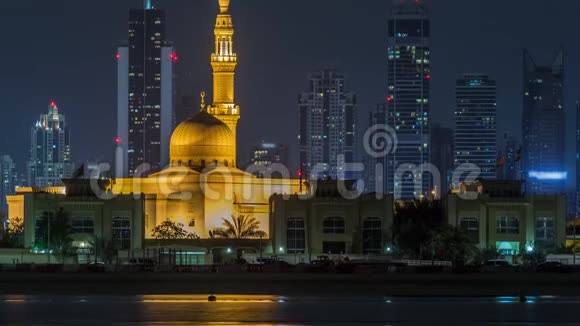 现代迪拜城市天际线随着夜晚拉希德哈代斯清真寺的时间推移水上摩天大楼被照亮视频的预览图