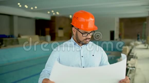 建筑工程师或建筑师戴橙色头盔在建筑背景上有施工计划视频的预览图