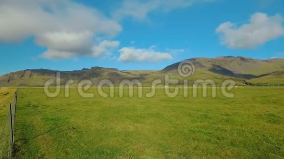 冰岛风景如画的绿色田野和静止的云层的全景靠近埃亚法亚拉霍卡尔火山视频的预览图