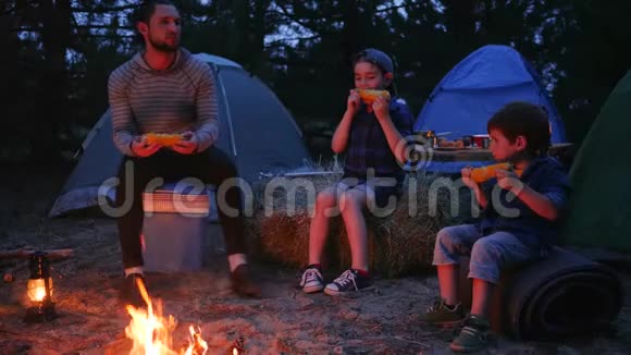 在暑假期间父母喝啤酒吃新鲜的黄玉米晚上在火焰附近吃晚餐视频的预览图