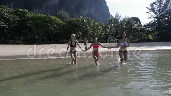女子组手挽手在水中奔跑男子站在山海滩上快乐的微笑女游客视频的预览图