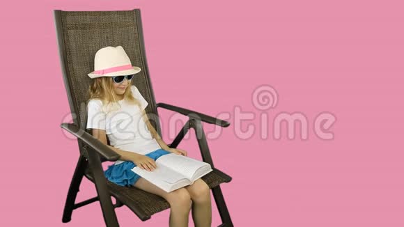 一个年轻的女孩坐在椅子上笑着读一本书视频的预览图