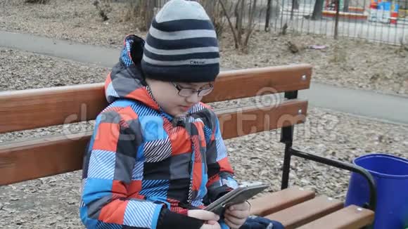 少年在外面的长凳上玩智能手机游戏视频的预览图