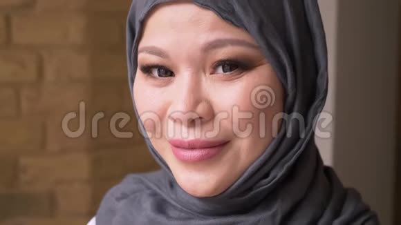 穆斯林成年女员工戴着头巾在工作场所看着摄像机开心地在室内微笑的特写镜头视频的预览图