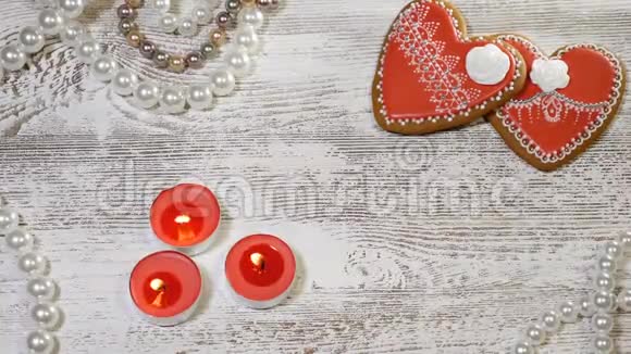 情人节的背景木制背景上的两个心形姜饼干茶烛和珍珠珠女性视频的预览图