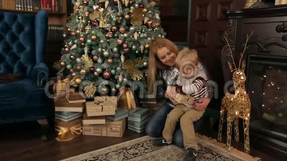 妈妈和儿子在圣诞树附近打开礼物视频的预览图