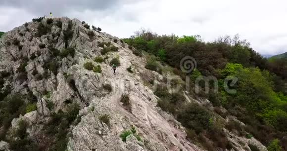 一名山地自行车手在山顶上举起自行车的空中射击视频的预览图