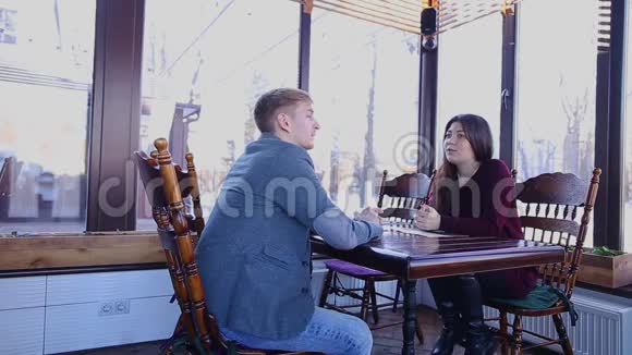 女青年和丈夫在咖啡馆的餐桌上交谈视频的预览图