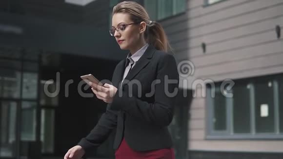 商界女性走在街上从智能手机上发送信息慢动作视频的预览图