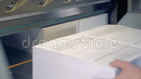 一名员工正在翻一堆纸这些纸的奇数边缘被一台工业切割机切断视频的预览图