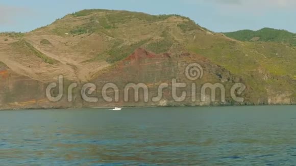 沿着马德拉岩石岸航行的白色渔船视频的预览图