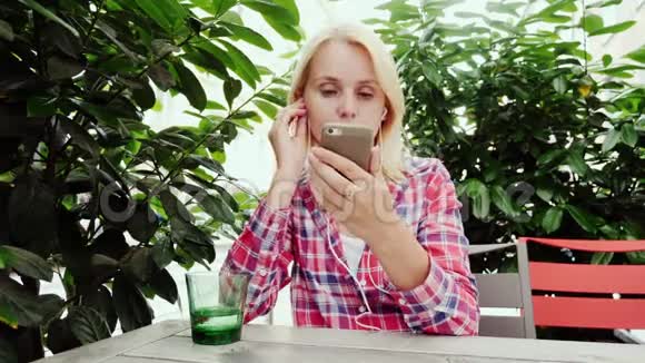 女人在舒适的咖啡馆里使用智能手机位于奥地利格拉茨市绿丛中的露台上视频的预览图