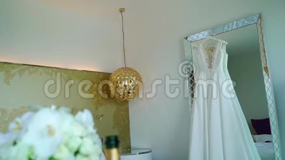 豪华酒店卧室镜子上的婚纱从白玫瑰中提取的金色花束视频的预览图