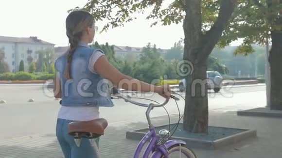一个年轻快乐的女孩骑着自行车在城市里走来走去喝着咖啡的肖像视频的预览图