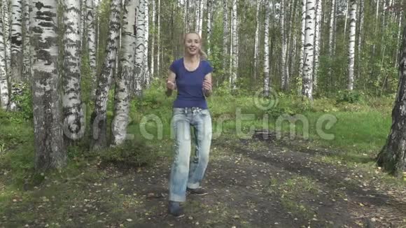 这位身材苗条的年轻女子穿着t恤和牛仔裤留着一头细密的长发在林中空地上与武术搏斗视频的预览图