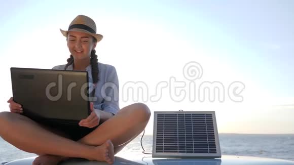 旅游业女孩坐在车顶背光笔记本电脑上说话充电太阳能阵列年轻女子坐在老式的视频的预览图