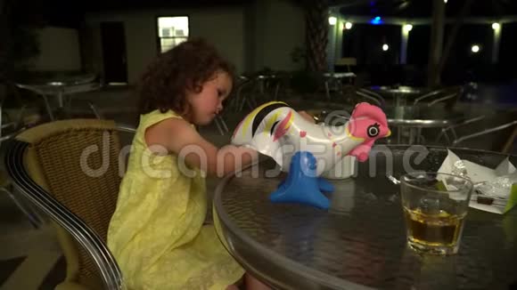 小女孩在夜餐馆的桌旁玩耍视频的预览图