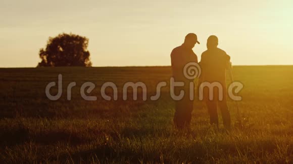 两个美国农民在日落时在田野里交流旁边是一把铲子视频的预览图